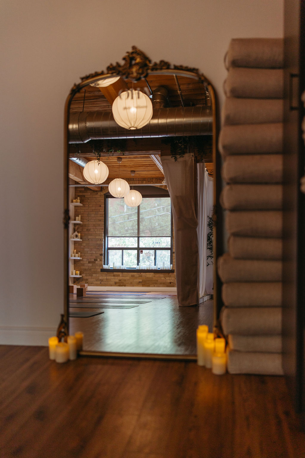 A calming view of the OHA Wellness studio in Liberty Village, Toronto, featuring soft lighting and a mirror reflecting the peaceful yoga space.